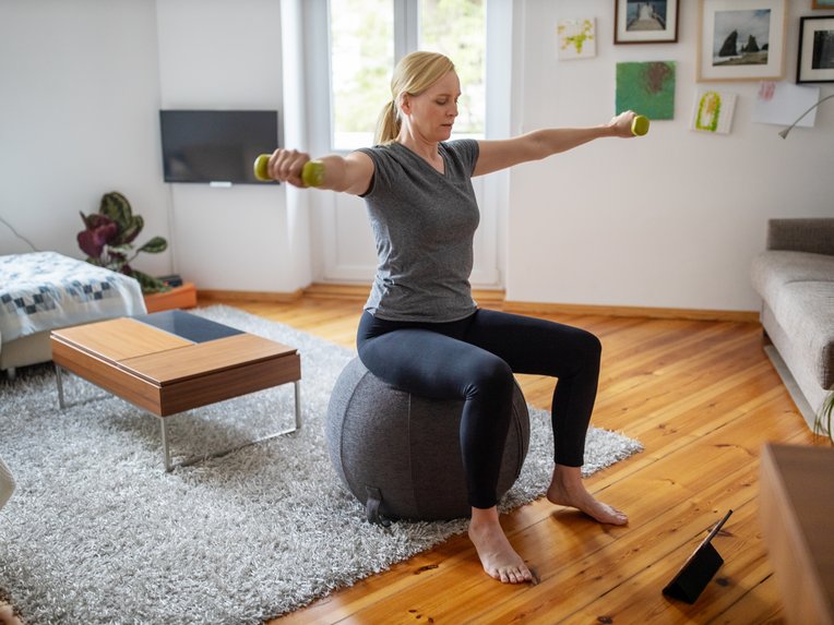 Eine Frau macht zu Hause Gymnastik&uuml;bungen.