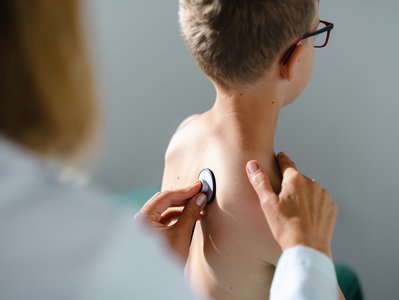 Eine &Auml;rztin h&ouml;rt einen kleinen Jungen mit einem Stethoskop ab.